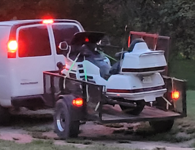 Picture of a motorcycle on the back of a trailer being pulled by a white van