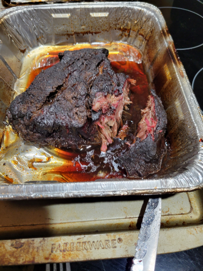 A smoked chuck roast in a pan, sitting on a cookie sheet. A knife appears in the bottom right corner.