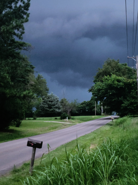 A vertical photo of storm clouds over a road