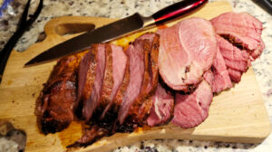 Image of sliced medium-rare sirloin roast on a wooden cutting board. A knife rests on the upper part of the cutting board. | Life Beyond the Day Job: Job Applications and More Smoking Adventures