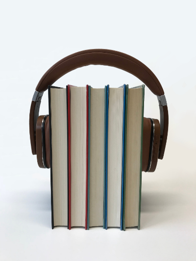 A side view of five books with a set of headphones over them.