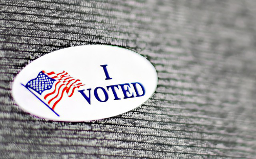 Image of an "I voted" sticker against a gray fabric background