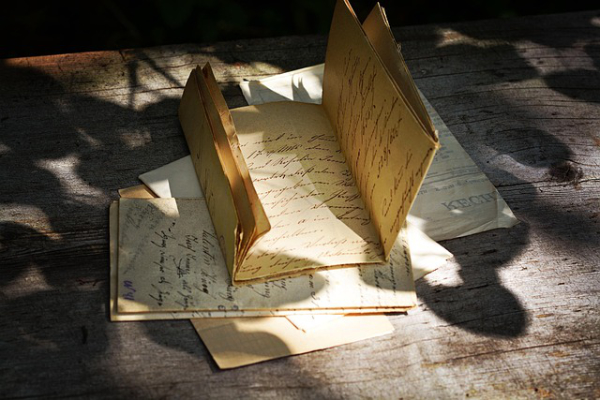 Vintage handwritten letters and postcards on a wooden table in sunlight. | I Missed That The First Time - a genealogy post